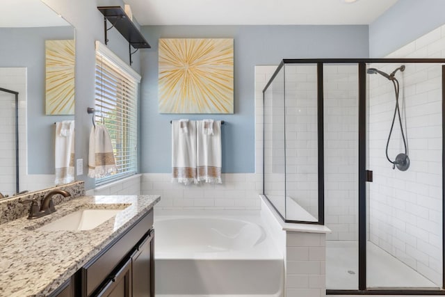 bathroom with a stall shower, a bath, and vanity