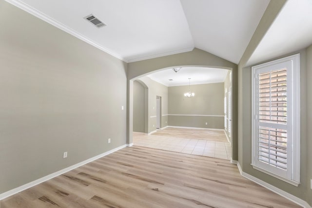 spare room with arched walkways, a chandelier, ornamental molding, light wood-type flooring, and baseboards