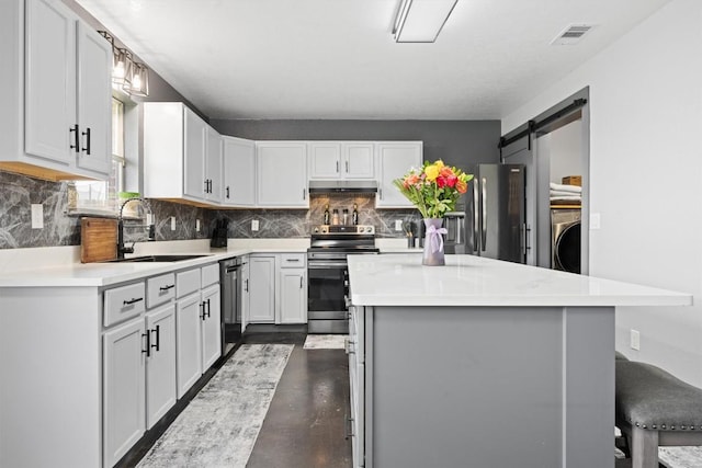 407 Osman Dr, Killeen, TX 76542 - kitchen featuring appliances with stainless steel finishes, a sink, under cabinet range hood, tasteful backsplash, and washer / clothes dryer