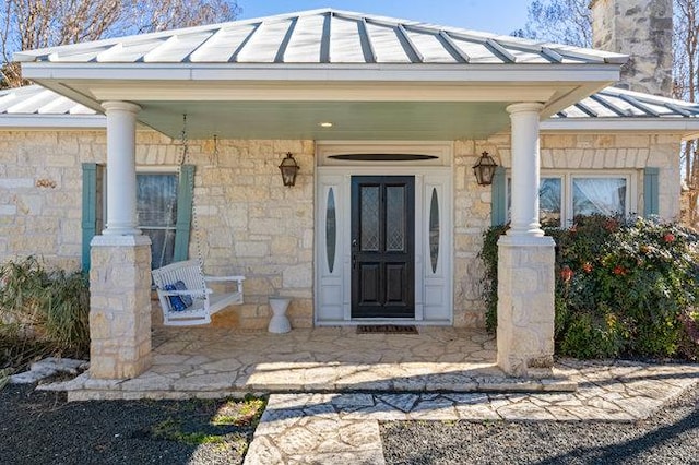 234 Loring, Stonewall, TX 78671 - property entrance with a standing seam roof, metal roof, covered porch, a chimney, and stone siding