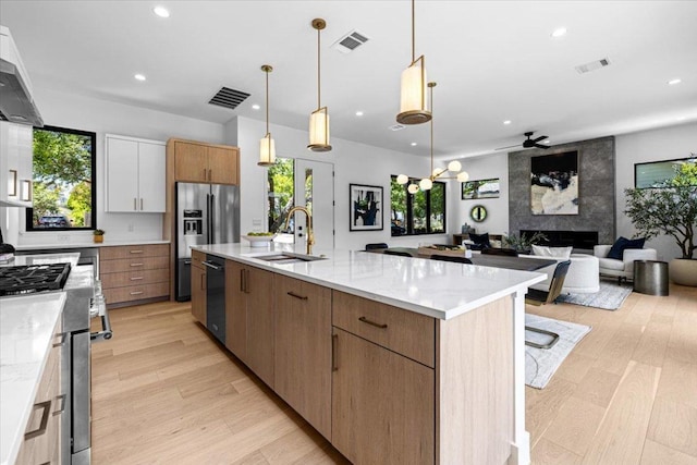 5409 Ave G Ave, Austin, TX 78751 - kitchen featuring appliances with stainless steel finishes, a large fireplace, open floor plan, recessed lighting, and light wood-type flooring