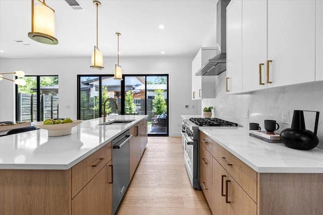 5409 Ave G Ave, Austin, TX 78751 - kitchen featuring appliances with stainless steel finishes, wall chimney exhaust hood, modern cabinets, light wood-style floors, and light stone counters