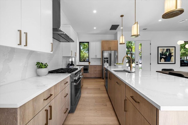 5409 Ave G Ave, Austin, TX 78751 - kitchen with stainless steel appliances, a sink, wall chimney exhaust hood, light wood finished floors, and backsplash