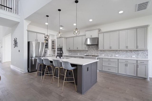 4916 Risana Bnd, Round Rock, TX 78665 - kitchen featuring appliances with stainless steel finishes, under cabinet range hood, a center island with sink, decorative backsplash, and recessed lighting