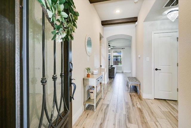 foyer with arched walkways, light wood-type flooring, ceiling fan, and baseboards