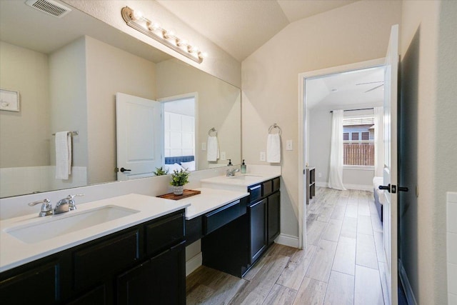 bathroom with vanity, lofted ceiling, wood finished floors, and baseboards