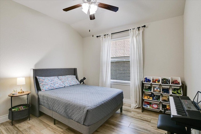 bedroom with vaulted ceiling, light wood-style flooring, baseboards, and a ceiling fan