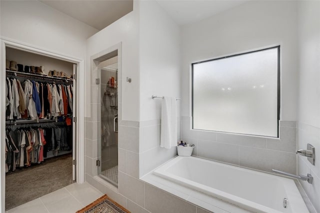 full bath featuring a spacious closet, a stall shower, a garden tub, and tile patterned floors