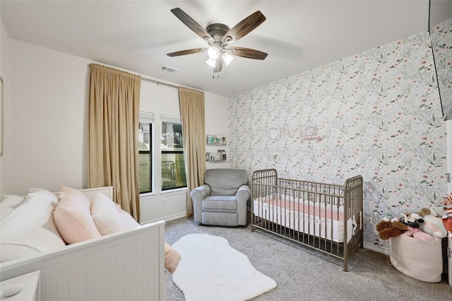 bedroom featuring carpet, ceiling fan, a crib, and baseboards