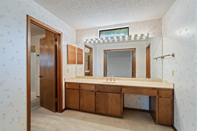 bathroom with wallpapered walls, a textured ceiling, and vanity