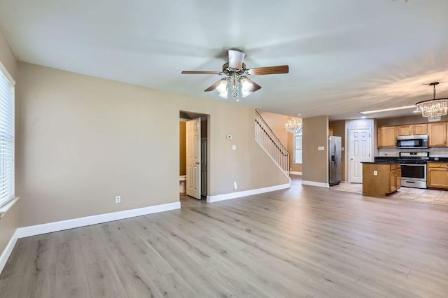 10517 S Canoa Hills Trl, Austin, TX 78717 - unfurnished living room with a chandelier, stairs, a ceiling fan, and light wood-type flooring