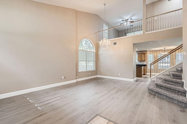10517 S Canoa Hills Trl, Austin, TX 78717 - unfurnished living room with a chandelier, a ceiling fan, stairway, light wood-type flooring, and a towering ceiling