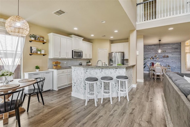 607 Westbury Ln, Georgetown, TX 78633 - kitchen featuring appliances with stainless steel finishes, light wood-style flooring, white cabinets, a breakfast bar, and recessed lighting
