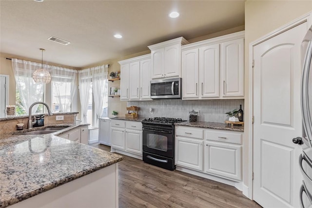 607 Westbury Ln, Georgetown, TX 78633 - kitchen with gas stove, stainless steel microwave, white cabinetry, light stone countertops, and tasteful backsplash