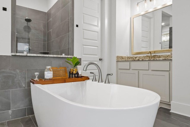 124 Low River Ln, Georgetown, TX 78628 - full bath featuring a soaking tub, vanity, a tile shower, tile patterned floors, and tile walls