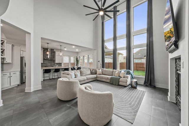 124 Low River Ln, Georgetown, TX 78628 - living room featuring a high ceiling, ceiling fan, baseboards, a fireplace, and dark tile patterned floors