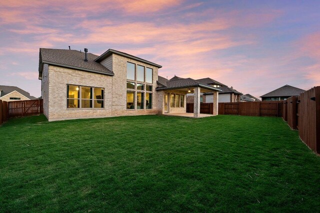 124 Low River Ln, Georgetown, TX 78628 - back of house at dusk featuring a patio and a fenced backyard