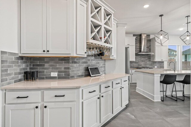 124 Low River Ln, Georgetown, TX 78628 - kitchen with wall chimney exhaust hood, backsplash, white cabinetry, a breakfast bar area, and gas cooktop
