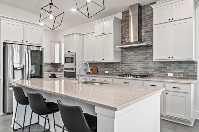 124 Low River Ln, Georgetown, TX 78628 - kitchen featuring a sink, wall chimney range hood, stainless steel appliances, decorative backsplash, and a center island with sink
