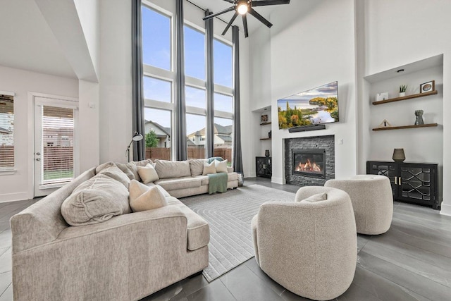 124 Low River Ln, Georgetown, TX 78628 - living area featuring a stone fireplace, a towering ceiling, a ceiling fan, and baseboards