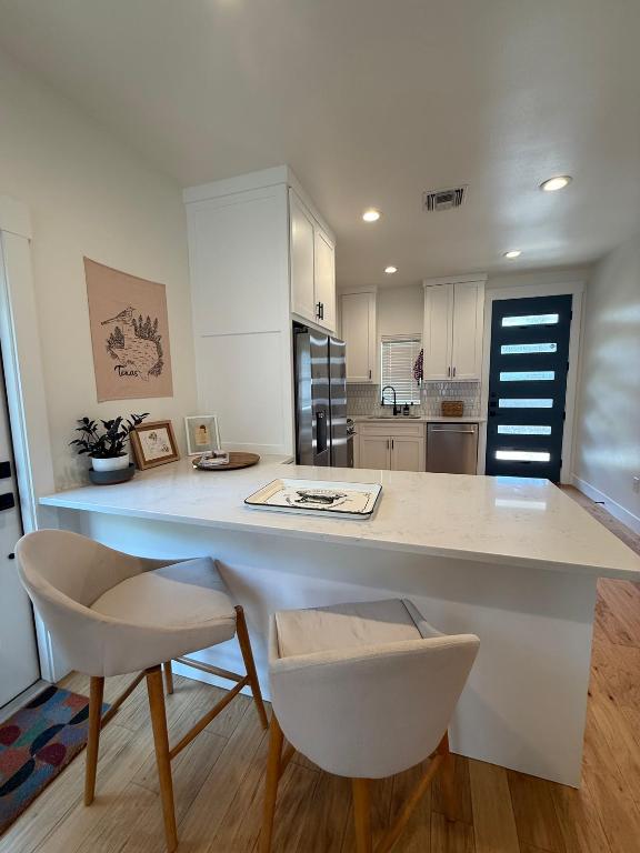 806 Philco Dr Unit 2, Austin, TX 78745 - kitchen with stainless steel appliances, a sink, white cabinetry, light wood finished floors, and tasteful backsplash