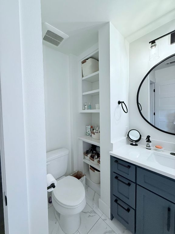 bathroom featuring marble finish floors, toilet, and vanity