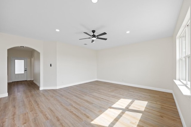 spare room with arched walkways, plenty of natural light, light wood-style flooring, recessed lighting, and ceiling fan