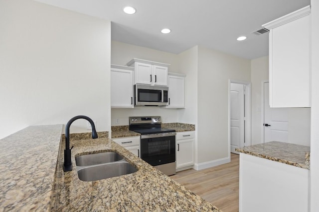 13221 Cabinet Dr, Manor, TX 78653 - kitchen featuring stainless steel appliances, light stone counters, light wood-style floors, white cabinets, and recessed lighting