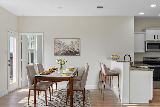 dining room featuring light wood-style floors, baseboards, and recessed lighting