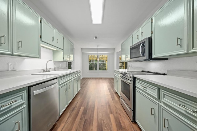 kitchen featuring appliances with stainless steel finishes, green cabinets, dark wood finished floors, and a sink