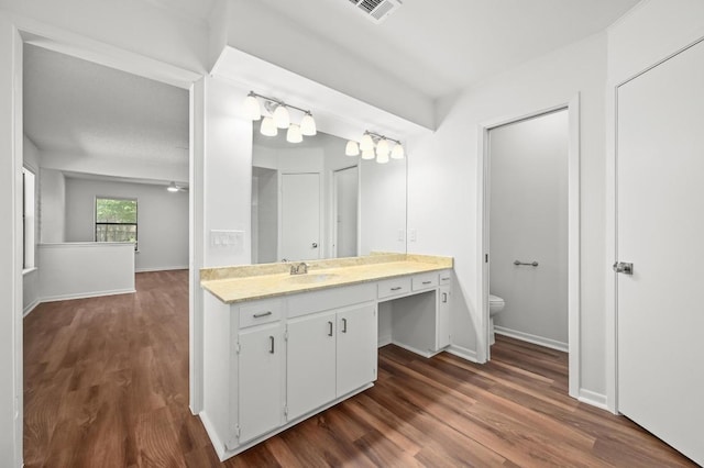 bathroom with toilet, wood finished floors, vanity, and baseboards