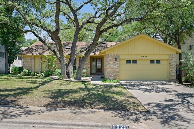 12025 Wycliff Ln, Austin, TX 78727 - view of front of home with brick siding, an attached garage, a front lawn, and concrete driveway