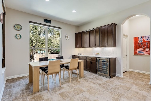 402 Dry Gulch Bnd, Cedar Park, TX 78613 - dining space with wine cooler, bar area, arched walkways, light stone finish flooring, and recessed lighting