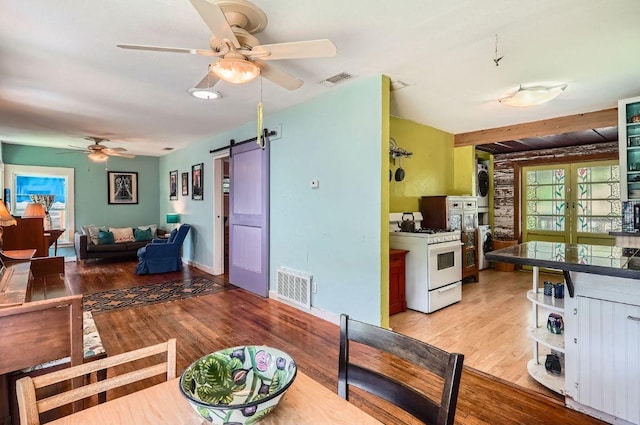dining area featuring a barn door, a ceiling fan, light wood-style floors, washer / clothes dryer, and baseboards