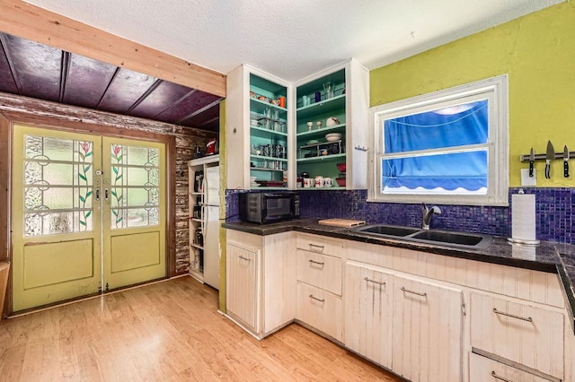 kitchen featuring french doors, a sink, black microwave, dark countertops, and light wood-style flooring