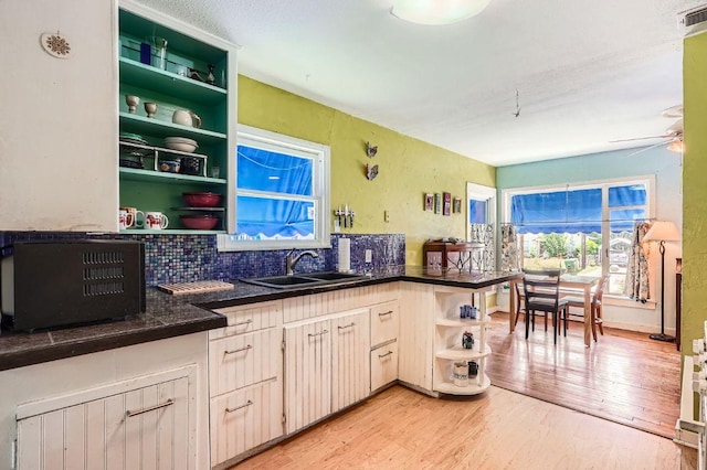kitchen featuring open shelves, a sink, dark countertops, light wood-style flooring, and ceiling fan