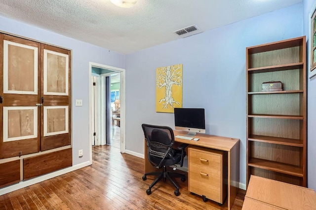home office with wood-type flooring, baseboards, and a textured ceiling