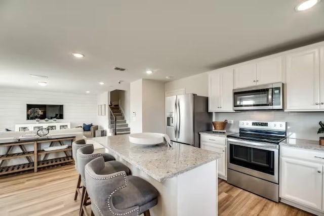 13417 Cerro Castellan Trce, Manor, TX 78653 - kitchen with appliances with stainless steel finishes, white cabinets, open floor plan, light stone counters, and a center island