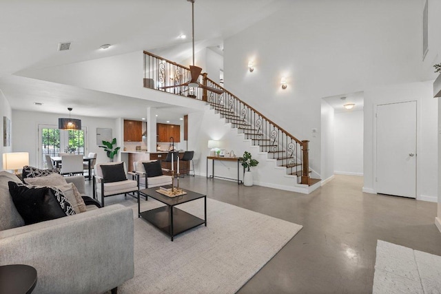 living room featuring finished concrete floors, stairs, baseboards, high vaulted ceiling, and recessed lighting