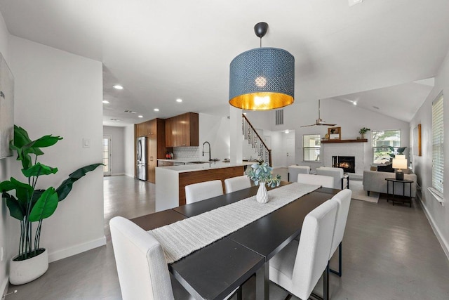 dining area featuring baseboards, stairs, a warm lit fireplace, recessed lighting, and lofted ceiling