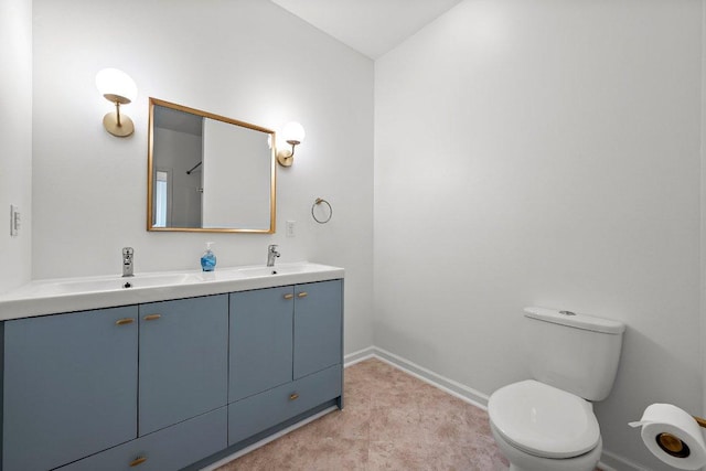 bathroom with baseboards, toilet, and double vanity