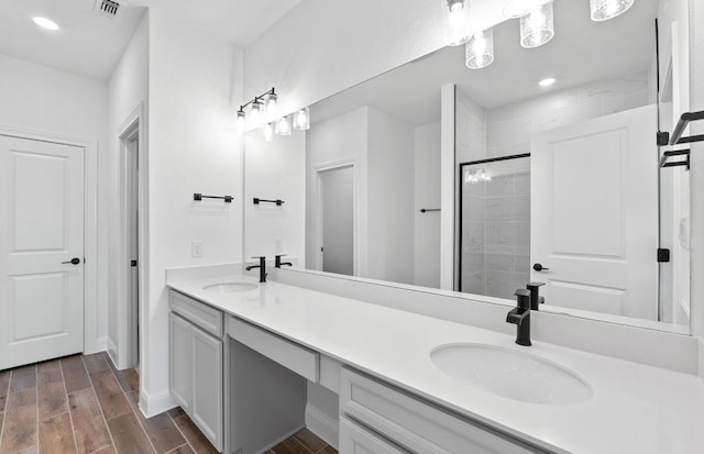 13404 Lapoynor St, Manor, TX 78653 - bathroom featuring double vanity, a tile shower, wood finished floors, and recessed lighting