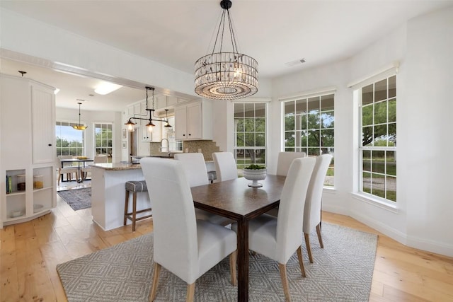 700 Longview Cir, Dripping Springs, TX 78620 - dining room with light wood-style floors, a chandelier, and baseboards