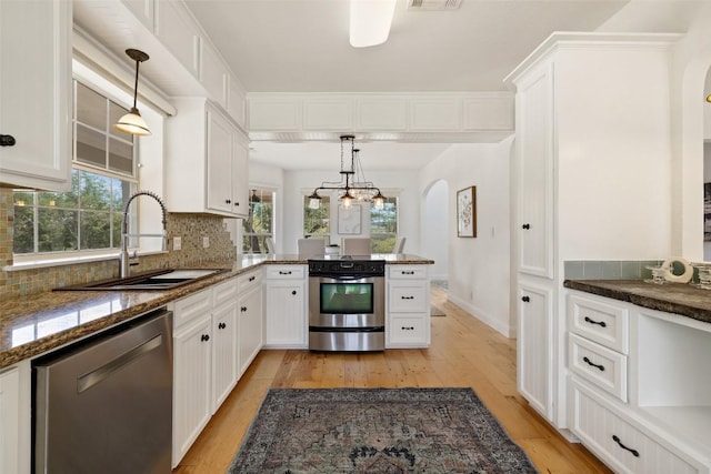700 Longview Cir, Dripping Springs, TX 78620 - kitchen featuring stainless steel appliances, a sink, arched walkways, light wood-style flooring, and white cabinetry