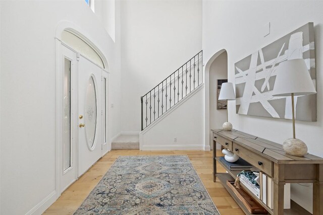 700 Longview Cir, Dripping Springs, TX 78620 - entrance foyer featuring light wood finished floors, a high ceiling, arched walkways, stairway, and baseboards