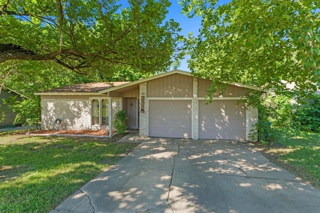 5105 Stone Gate Dr, Austin, TX 78721 - view of front facade with a garage, brick siding, driveway, and a front yard