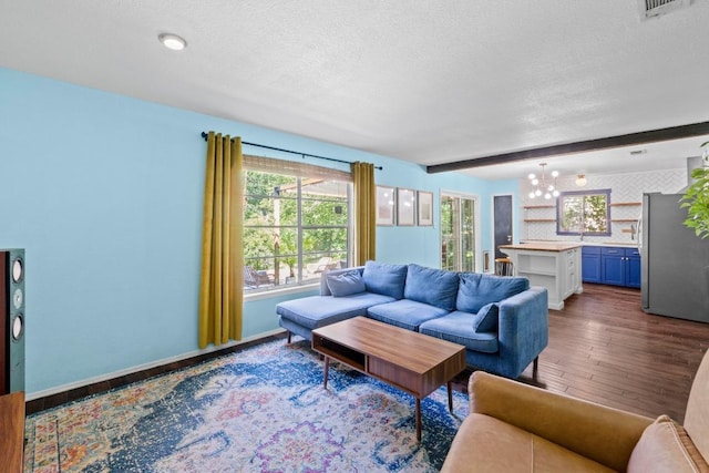 5105 Stone Gate Dr, Austin, TX 78721 - living room with a textured ceiling, wood finished floors, a chandelier, beamed ceiling, and baseboards