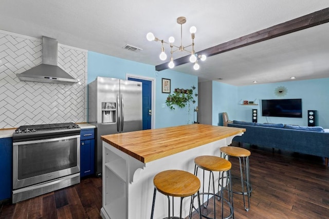 5105 Stone Gate Dr, Austin, TX 78721 - kitchen featuring appliances with stainless steel finishes, wall chimney exhaust hood, blue cabinets, wooden counters, and decorative backsplash