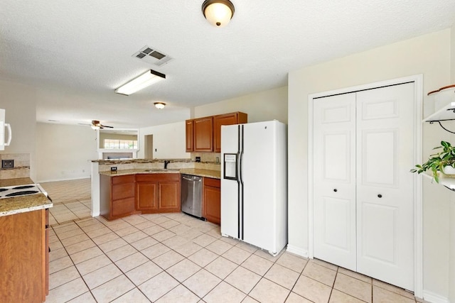 kitchen with white refrigerator with ice dispenser, dishwasher, a peninsula, brown cabinetry, and a sink