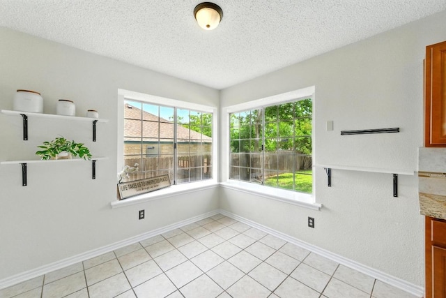 unfurnished dining area with a textured ceiling and baseboards